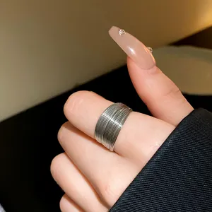 Macro detail of a stylish minimalist silver multi-layer wire textured ring on a person's finger.