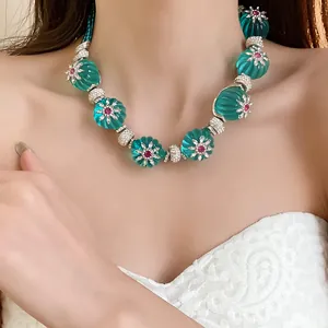 Dettaglio di una collana vintage con perle di resina verde testurizzate e motivi floreali