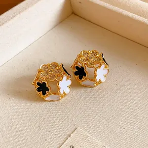 Detailed close-up of gold flower stud earrings with black and white enamel and crystals