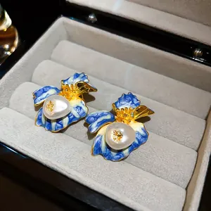 Close-up detail of blue enamel flower earrings with pearls inside a luxury jewelry box