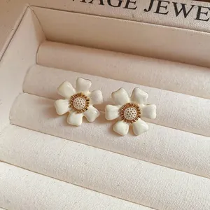 Close-up of elegant cream flower stud earrings with golden centers in a jewelry box