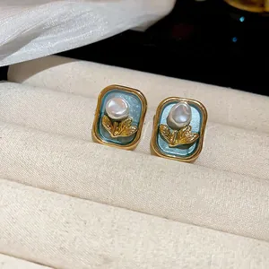 Detailed view of elegant teal enamel earrings with pearl and gold floral accents in vintage frames