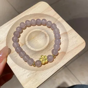 Elegante bracciale in perle di vetro lavanda con ciondolo a fiore di prugna dorato su legno