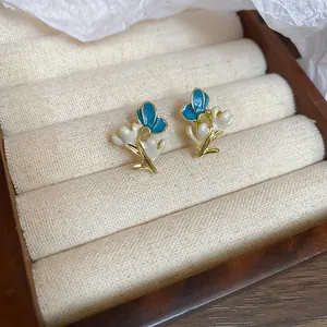 Close-up of elegant blue and white flower enamel stud earrings on a display tray