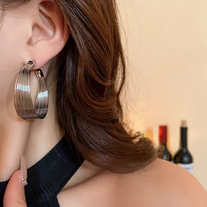 Large silver multi-layered hoop earrings with striated texture for a minimalist cool style
