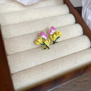 Detailed view of sweet floral enamel earrings displayed on a beige velvet tray