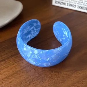 Detailed macro view of a chunky blue acrylic open cuff bracelet with textured marbled finish