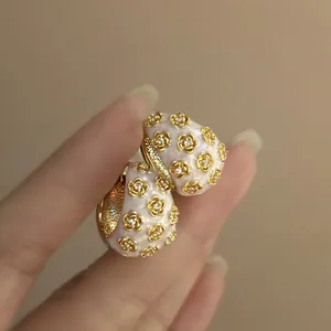 Close-up of elegant flower enamel earrings with sparkling crystal details held by hand