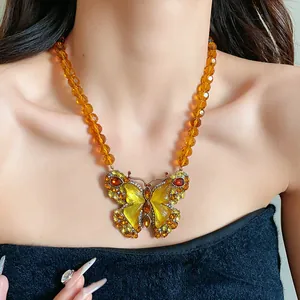 Gros plan sur un collier papillon vintage avec perles en verre ambré et strass