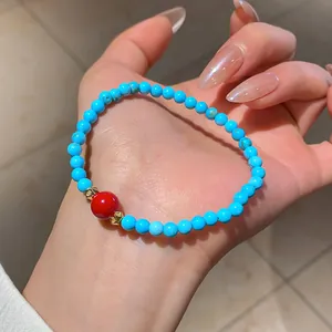 Bracciale di perline turchesi con perlina rossa centrale e dettagli dorati