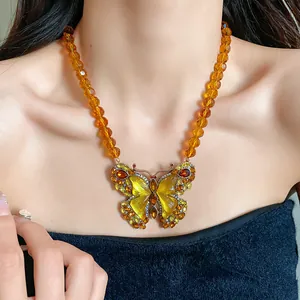Gros plan détaillé du pendentif papillon vintage et collier de perles de verre ambrées