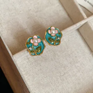 Detailed view of floral enamel earrings featuring pearls and sparkling crystals.