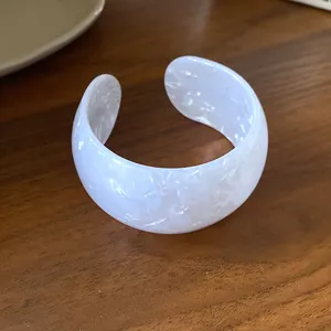 Close-up of a white iridescent acrylic open cuff bracelet with elegant marbled texture