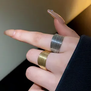 Macro detail of wide ribbed texture metal rings in gold and silver on model hand