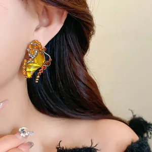 Boucle d'oreille papillon ambre vintage avec strass jaunes portée par un mannequin