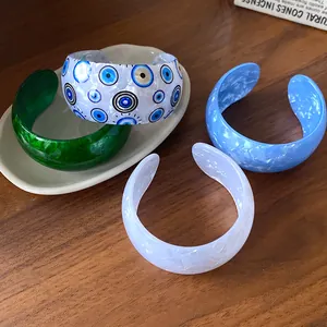 Detailed view of chunky acrylic cuff bracelets featuring marble and evil eye patterns.