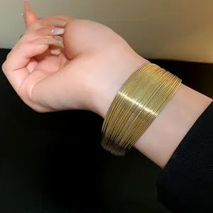Detailed macro view of a stylish gold multi-layer wide metal cuff bracelet on a wrist
