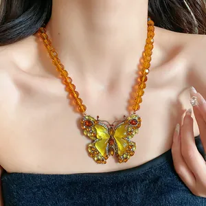 Détail d'un collier papillon vintage avec perles de verre ambrées et pendentif