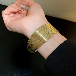 Detailed view of a wide multi-strand gold cuff bracelet worn on the wrist