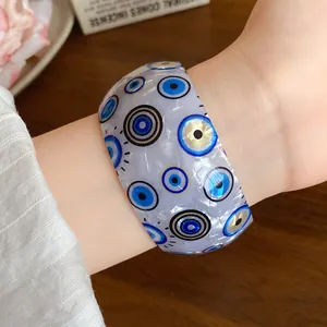 Detailed macro view of iridescent acrylic cuff bracelet with blue evil eye pattern