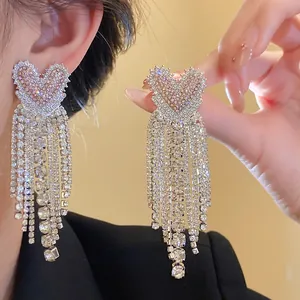 Primo piano di orecchini a nappa a forma di cuore con strass rosa brillanti.
