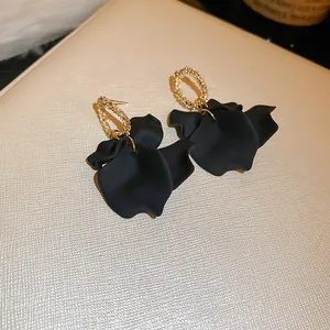 Macro detail of vintage French style black petal earrings with textured golden hoops