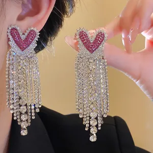 Dettaglio degli orecchini a nappa a forma di cuore con strass rossi e zirconi bianchi