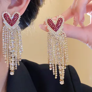 Dettaglio orecchini a cuore in zircone rosso con nappe lunghe di strass molto brillanti