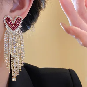 Dettaglio ravvicinato di orecchini a cuore in zircone rosso con eleganti nappe lunghe