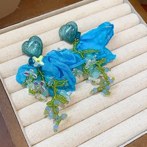 Detailed view of handmade blue heart chiffon flower earrings with green beaded tassels