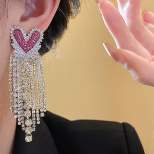 Dettaglio di orecchini a cuore in zircone con eleganti e lunghe nappe di strass