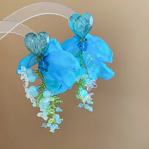 Detail shot of bright blue heart chiffon flower tassel earrings with beaded accents