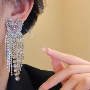 Dettaglio ravvicinato di lussuosi orecchini a nappa con strass a forma di cuore sul modello
