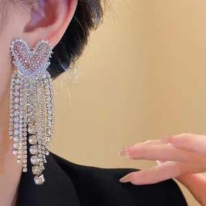 Primo piano di orecchini a nappa color argento con cuore rosa e zirconi brillanti.