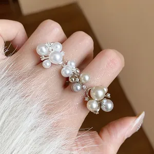 Elegant detailed shot of French style zircon flower and pearl cluster ring on finger