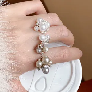 Detailed view of elegant French style zircon flower cluster pearl rings worn on hand