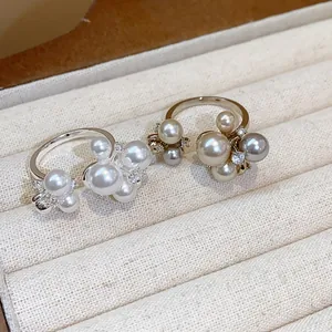 Detail macro view of French style pearl and zircon flower rings in a beige jewelry box
