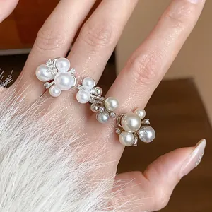Detailed macro view of elegant French style zircon flower and pearl ring on finger