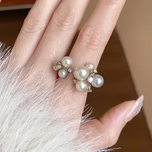 Detail of French zircon flower ring with white and grey pearls on finger