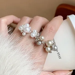 Detailed view of elegant French style zircon flower and faux pearl rings on fingers