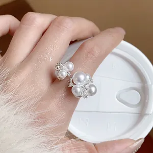 Detail view of a French zircon pearl flower ring on a finger with a soft focus background.
