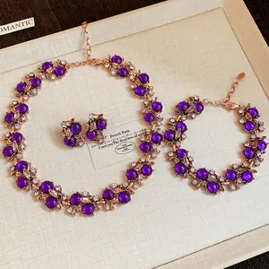 Vintage floral jewelry set featuring purple beads and rose gold leaf details in a tray.