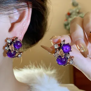 Close-up of elegant vintage-style purple bead earrings with gold leaf and rhinestones.