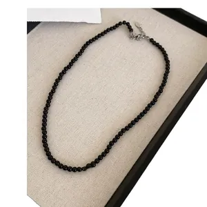 Elegant black beaded adjustable necklace displayed on a minimalist textured jewelry tray