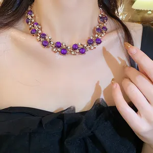 Detailed view of luxury vintage leaf necklace with purple stones and diamonds on model.