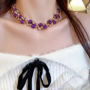 Detail view of a vintage rose gold necklace featuring purple beads and leaf designs