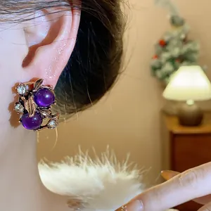 Detailed view of elegant purple gemstone earrings with leaf motifs and sparkling rhinestones