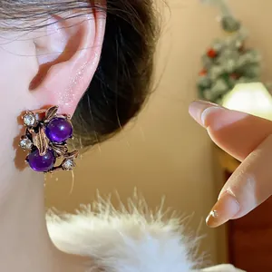 Vintage palace style earrings with purple beads and rhinestones on model's ear