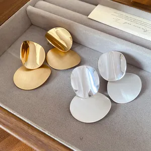 Close-up of gold and silver brushed metal earrings showcasing the textured finish detail