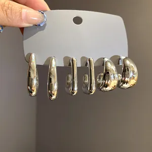 Detail showing a set of three pairs of silver-tone irregular geometric chunky earrings.